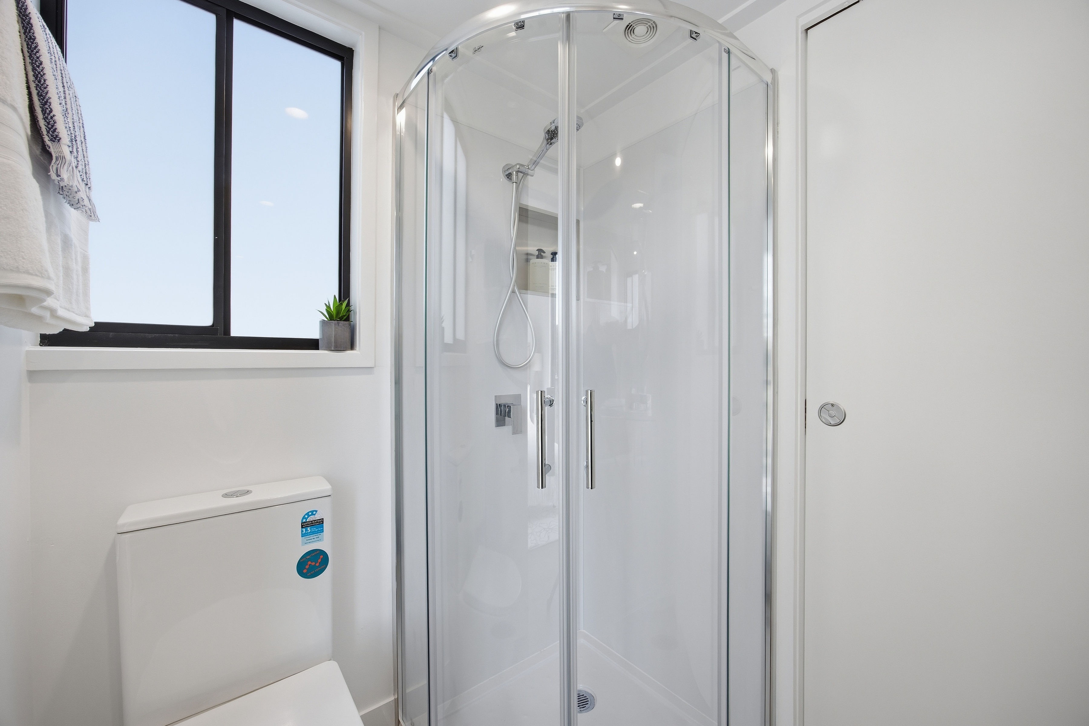 Compact tiny home bathroom with shower and black-framed window