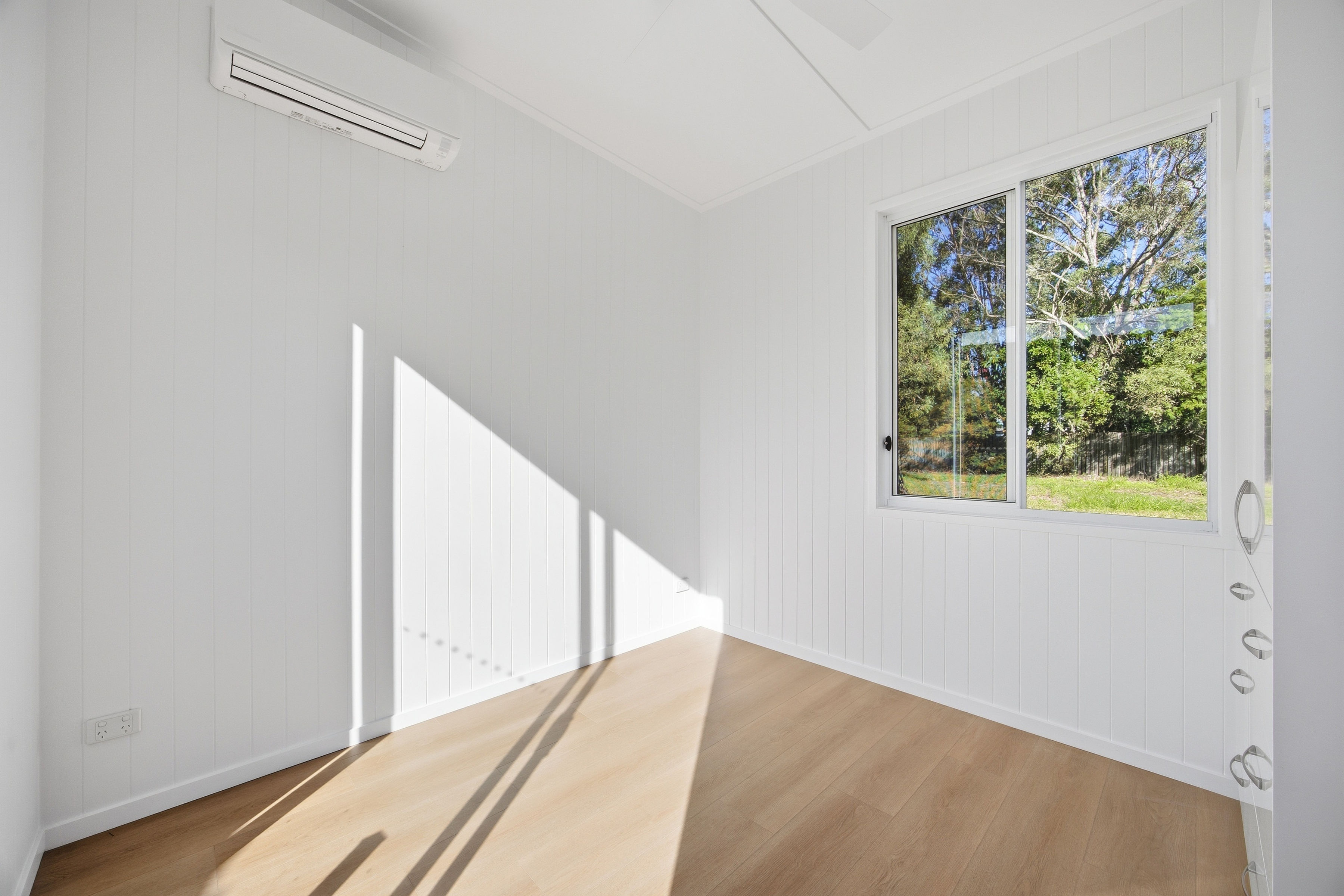 Fresh white tiny home bedroom with timber floors