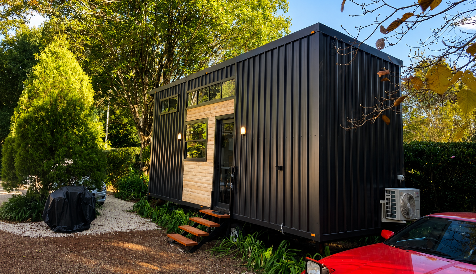 Black-clad tiny home with timber entry steps at dusk